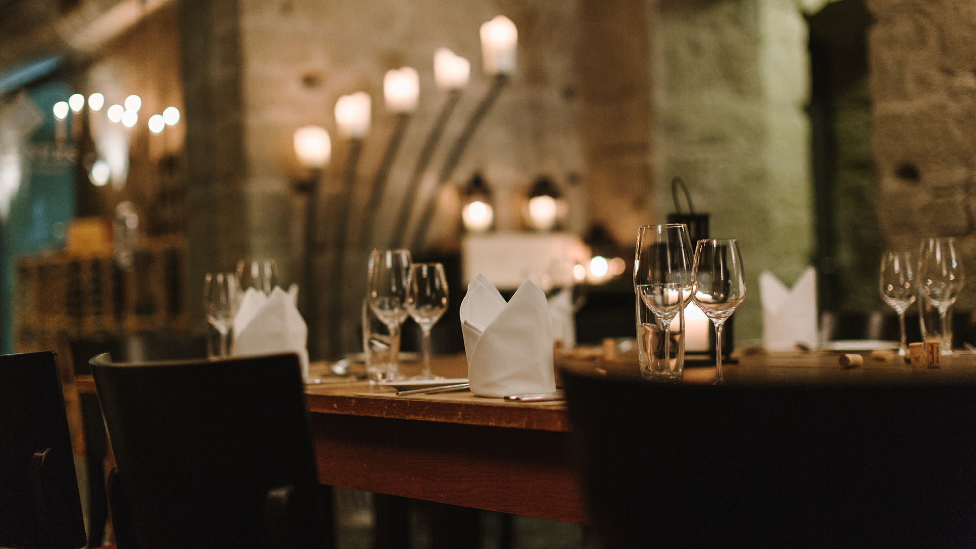 Festively laid table in the vaulted cellar with candles in the background