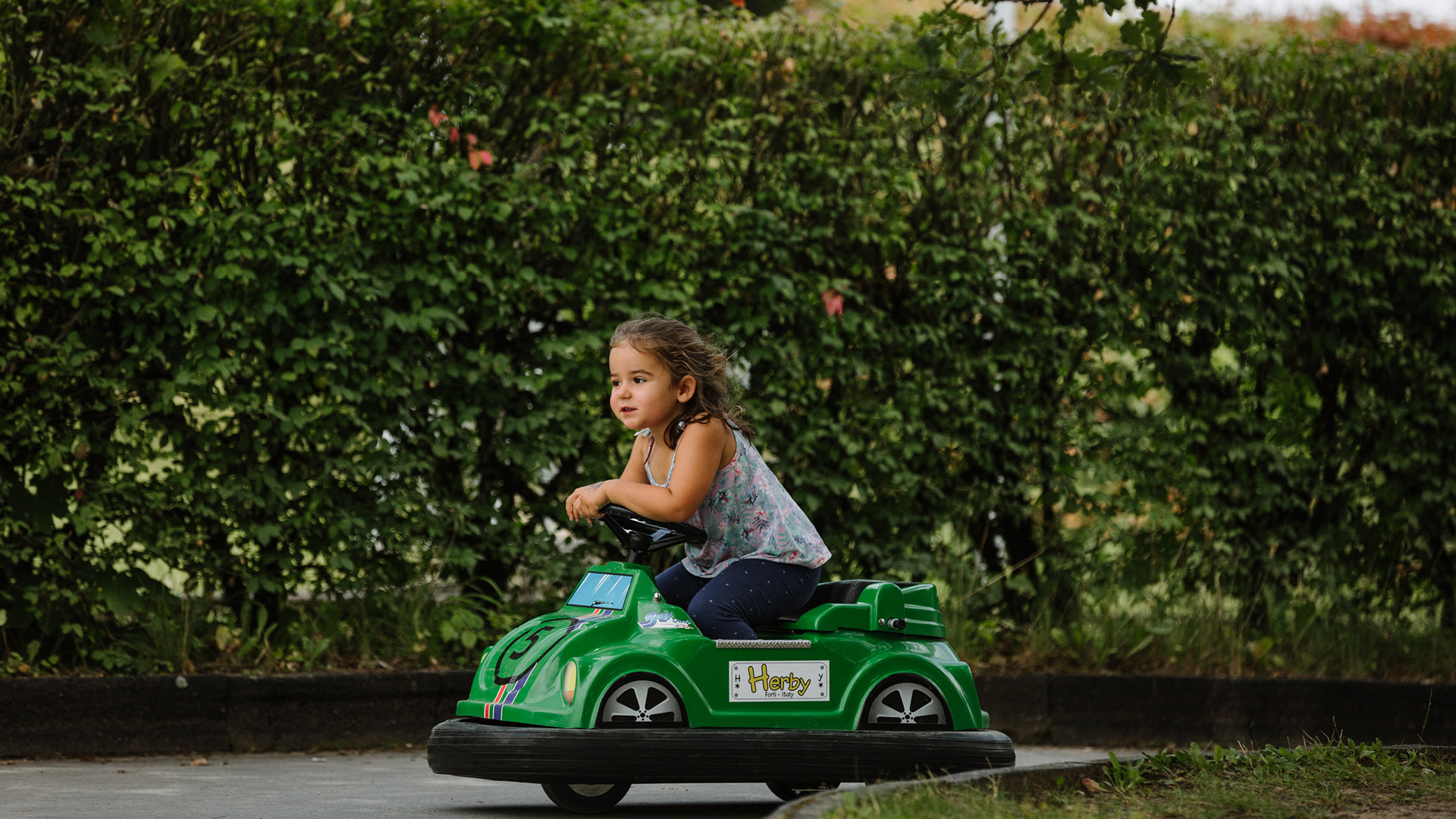 Une petite fille concentrée circule sur la piste dans sa voiture miniature