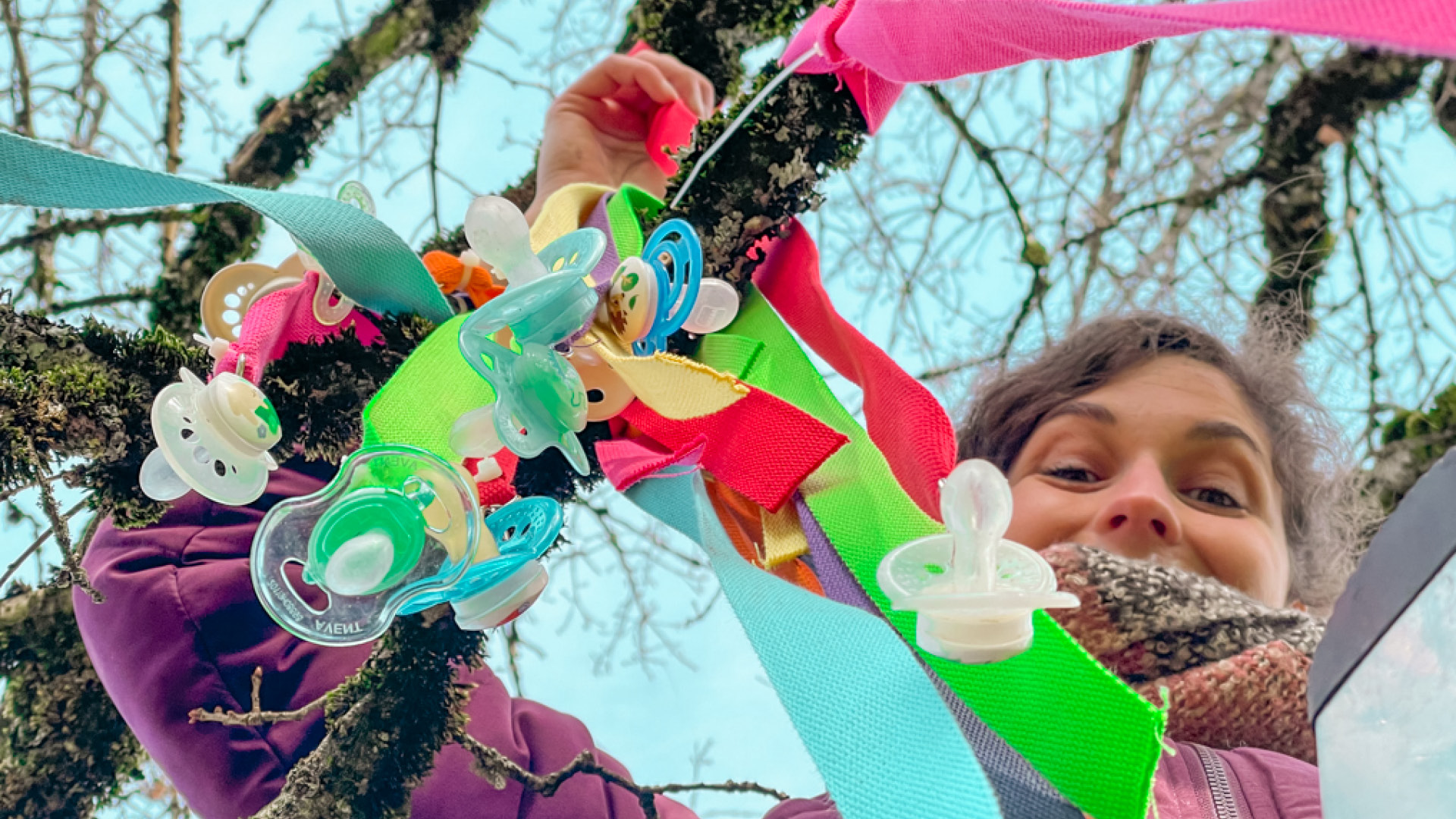 A person hangs the pacifiers on a branch.