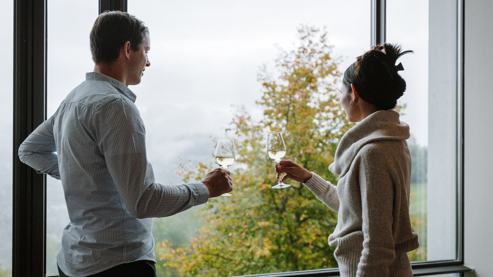 A couple raising their glasses in a toast in front of the facade window in the Wytsicht banqueting room