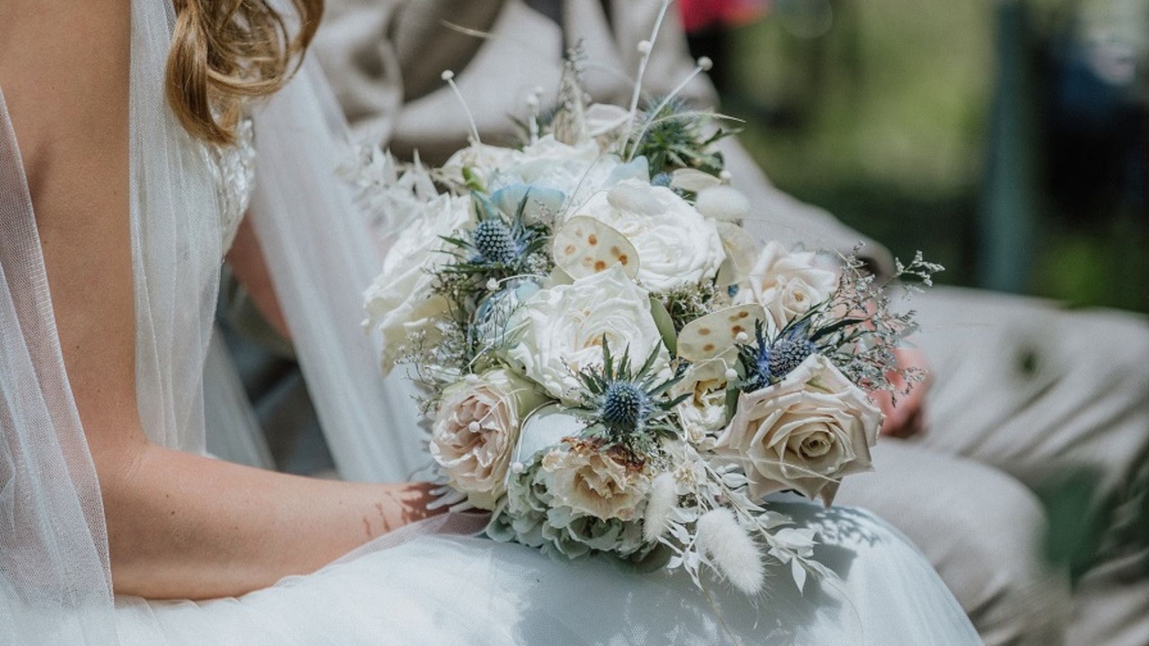 Braut in weissem Kleid hält Brautstrauss in taupe Farbe
