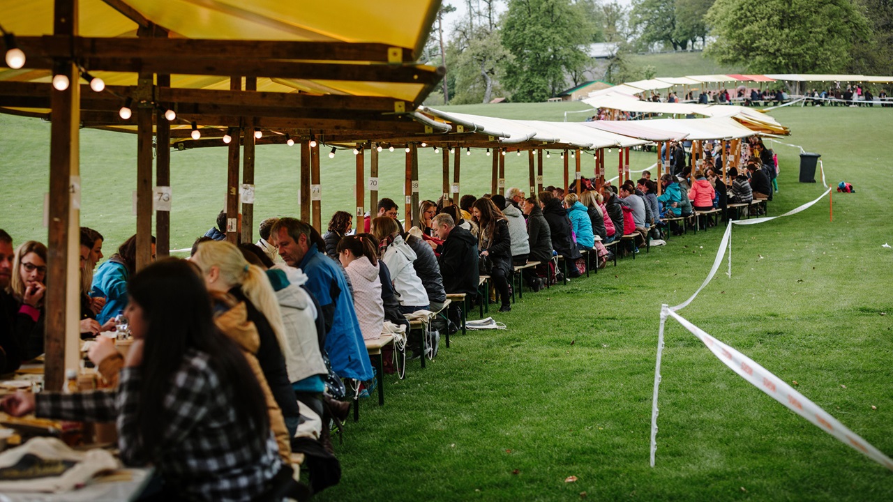 People eating at a long, laid fixed table on the Gurten meadow 
