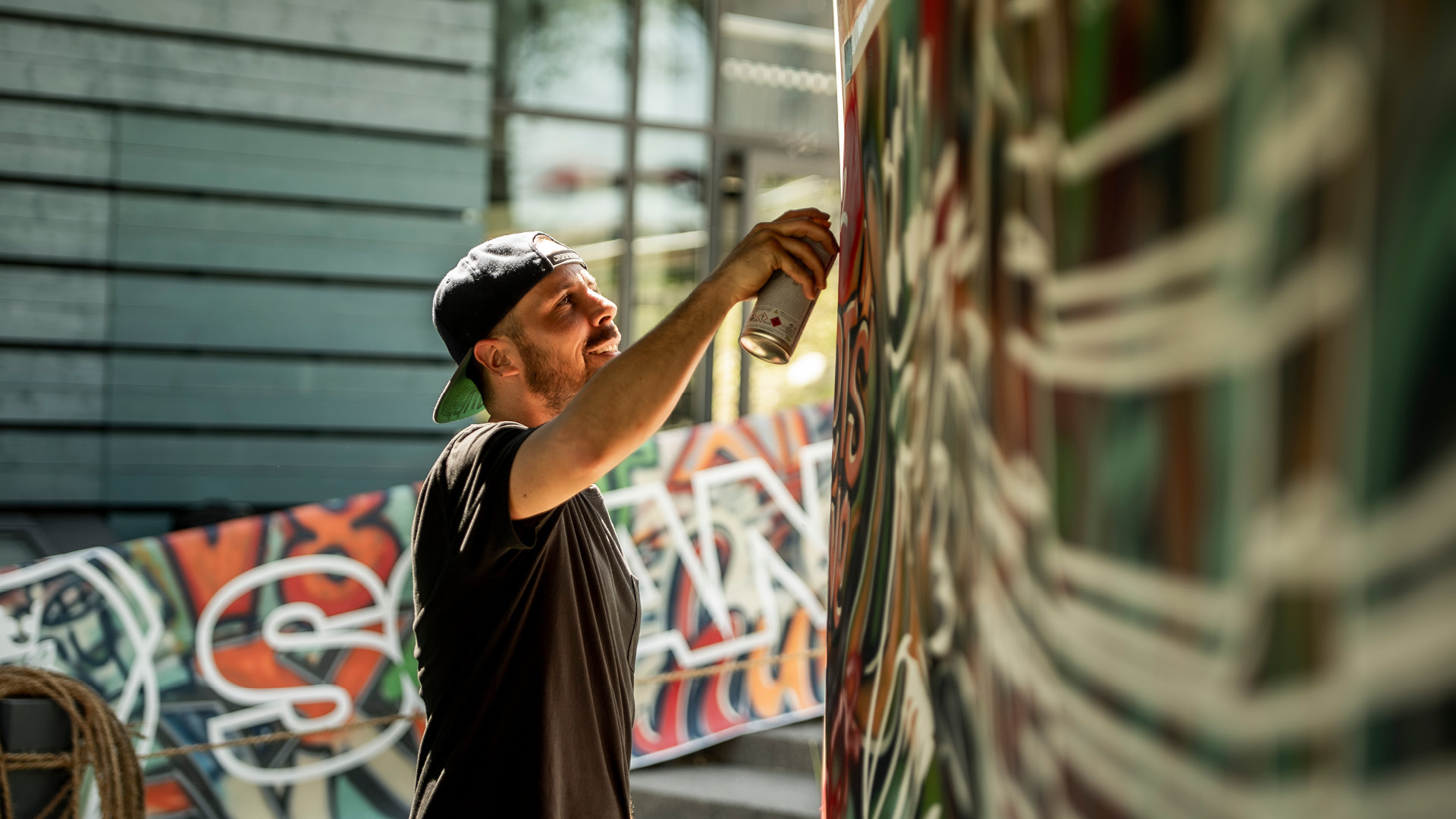 Mann am Graffiti sprayen bei einem Teamevent vom Gurten