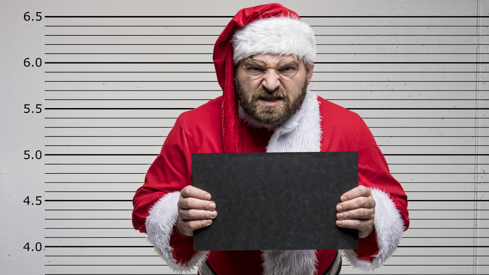 Grim man in Father Christmas costume in front of prison wall