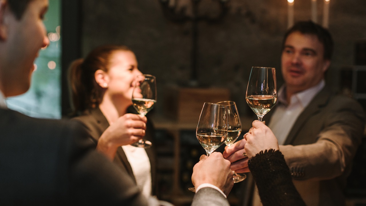 People raising a toast with a glass of white wine