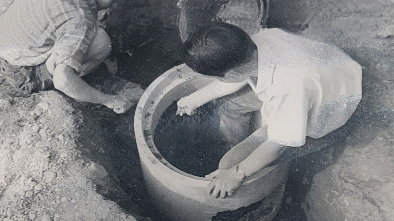 The boys climb into a manhole.