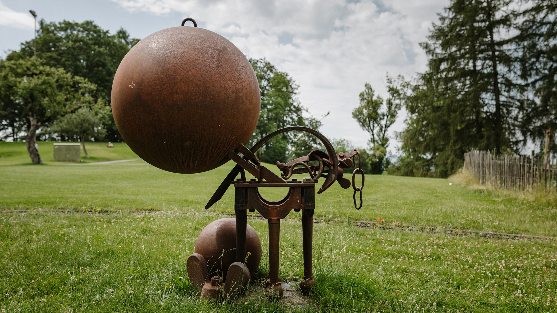 A rusting metal figure is exhibited in the park. 
