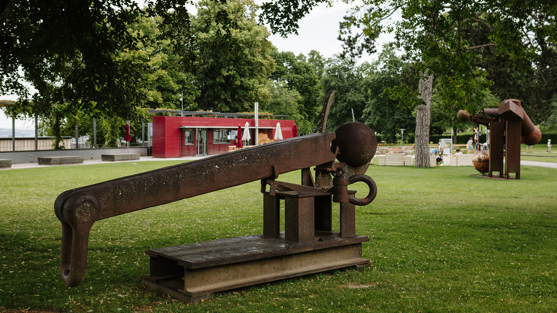 The brown statue by Bernhard Luginbühl stands in the park. 