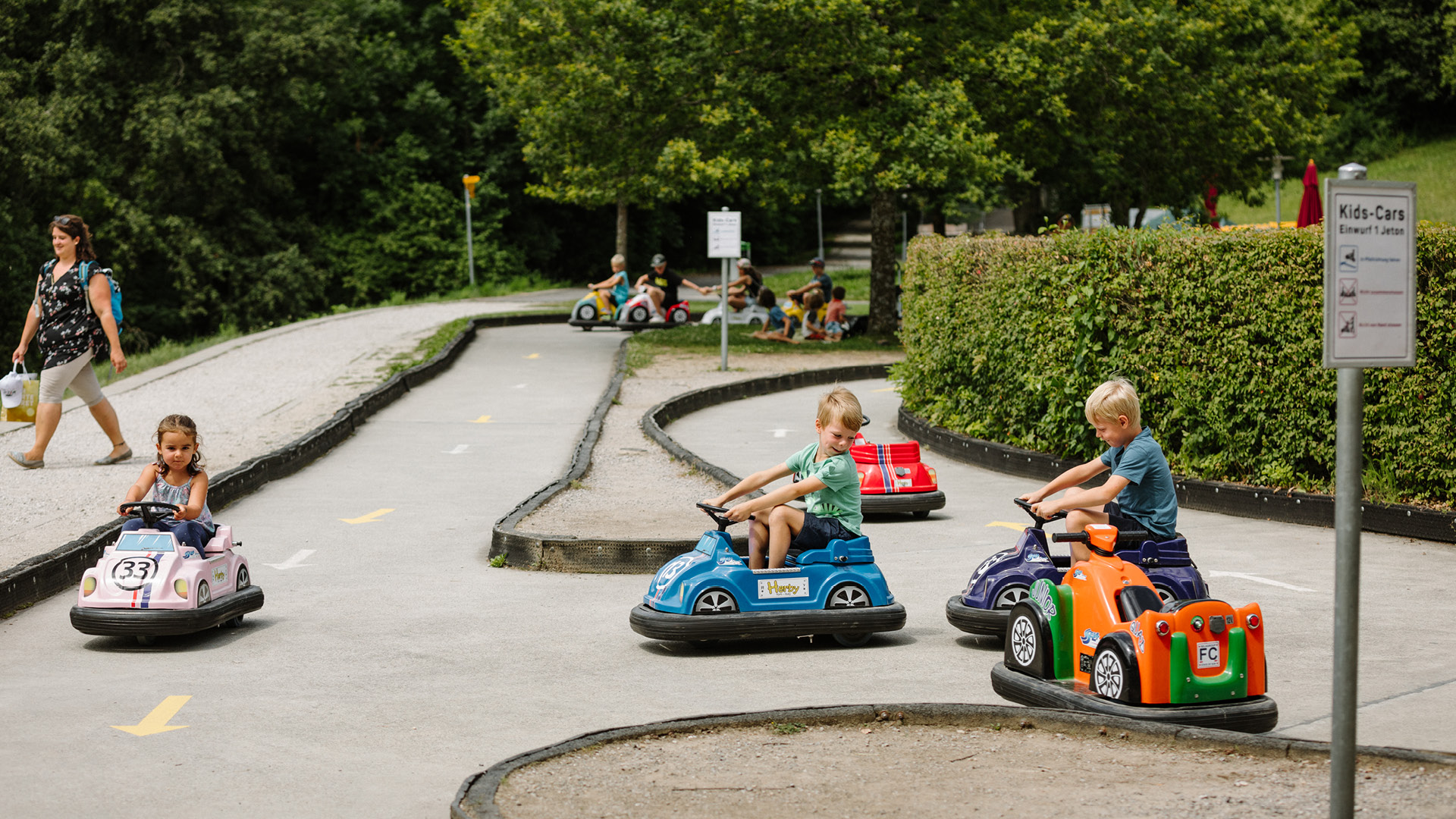 Drei kleine Kinder fahren auf kleinen Fahrzeugen um die Wette