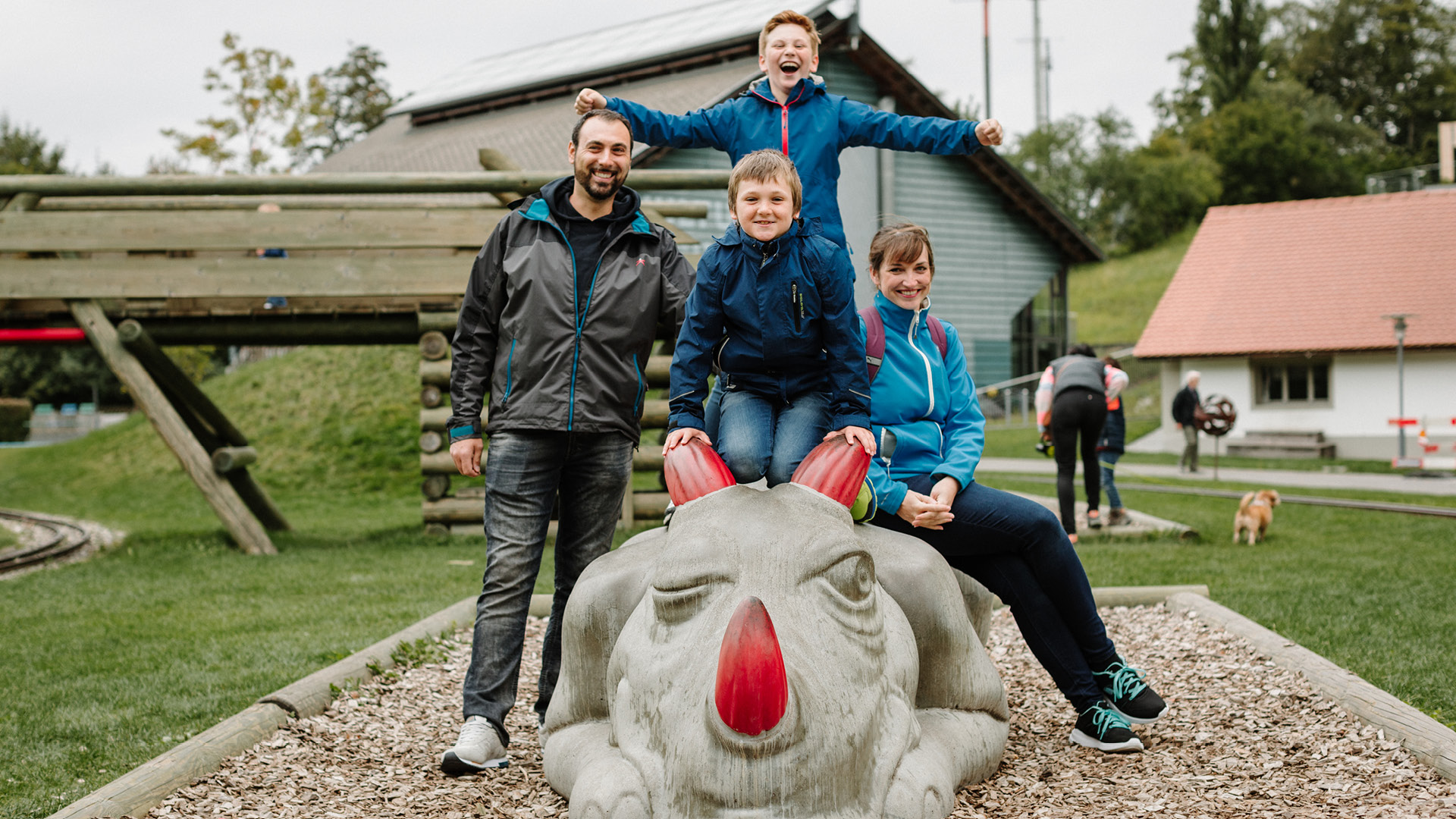 A family poses on the concrete dragon at the playground