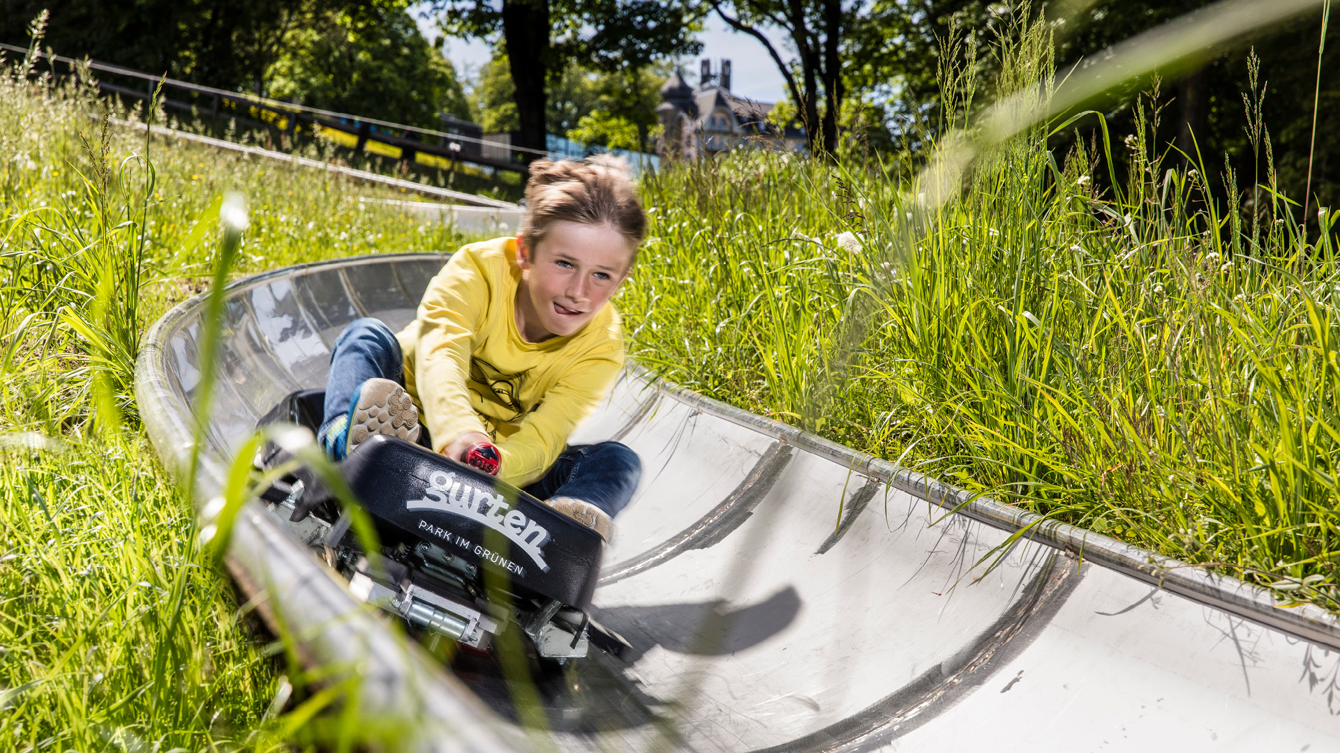 A delighted child racing down the toboggan run
