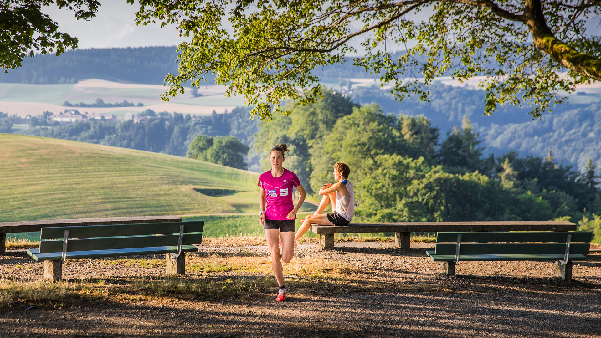 Two joggers by the Ostsignal. One is stretching on a bench, the other is setting off. 