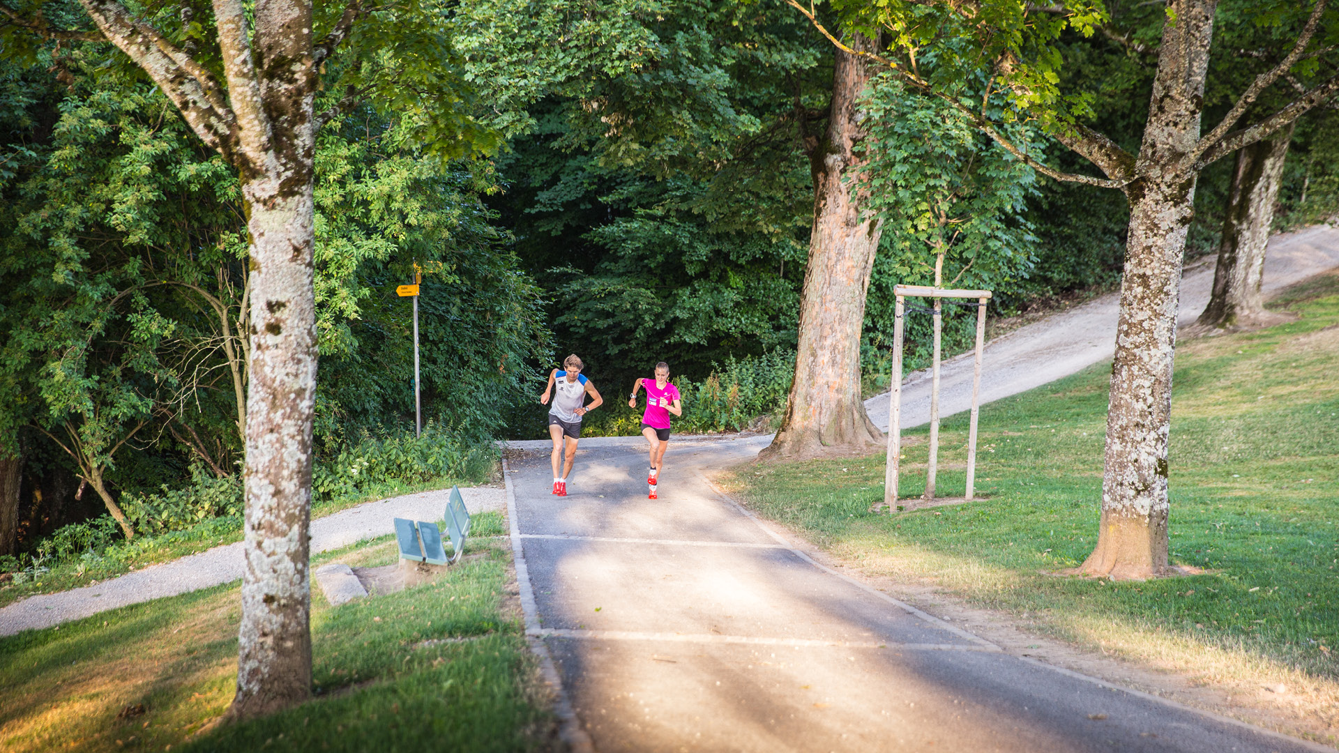 Two joggers sprinting up a steep slope.