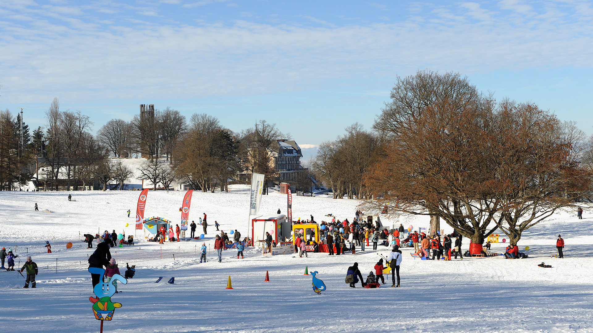 Der Gurten ist mit Schnee bedeckt. Jede Menge Menschen sind mit dem Schlitten und mit Ski unterwegs. In der Mitte befindet sich der Kinderskilift