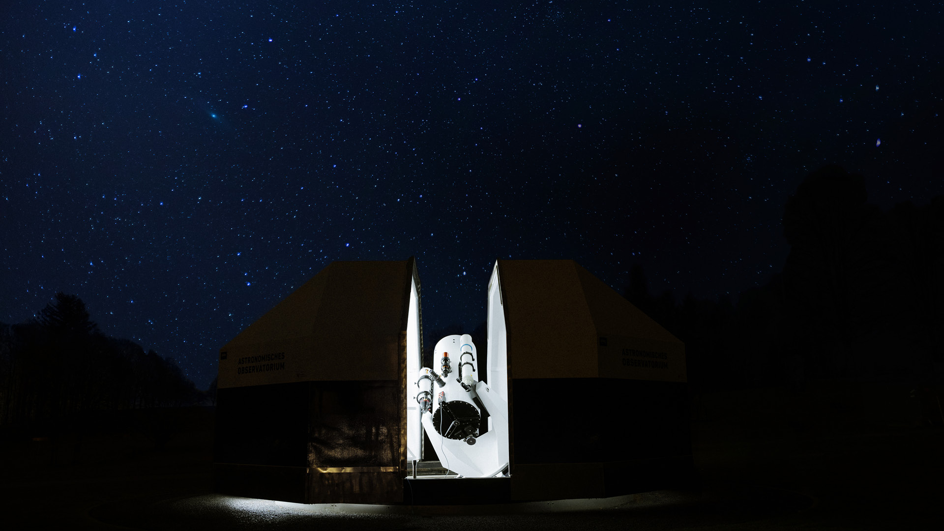 The illuminated observatory on the Gurten with a starry sky in the background.