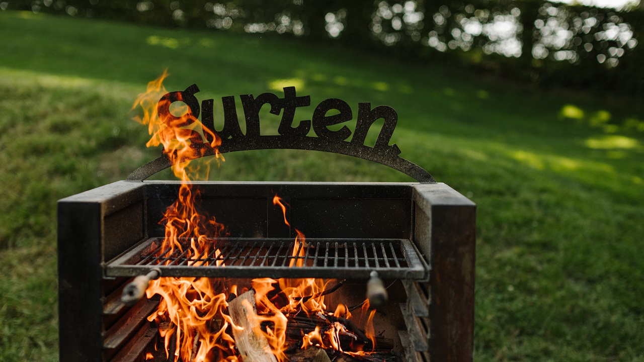 Burning wood in the fire. The barbecue is decorated with the Gurten logo. 