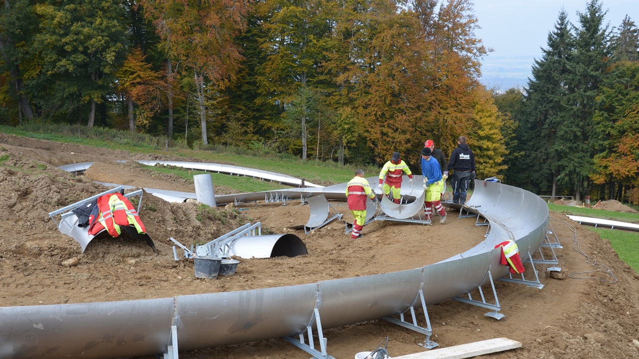 The toboggan run being built. Four construction workers assembling the individual parts. 