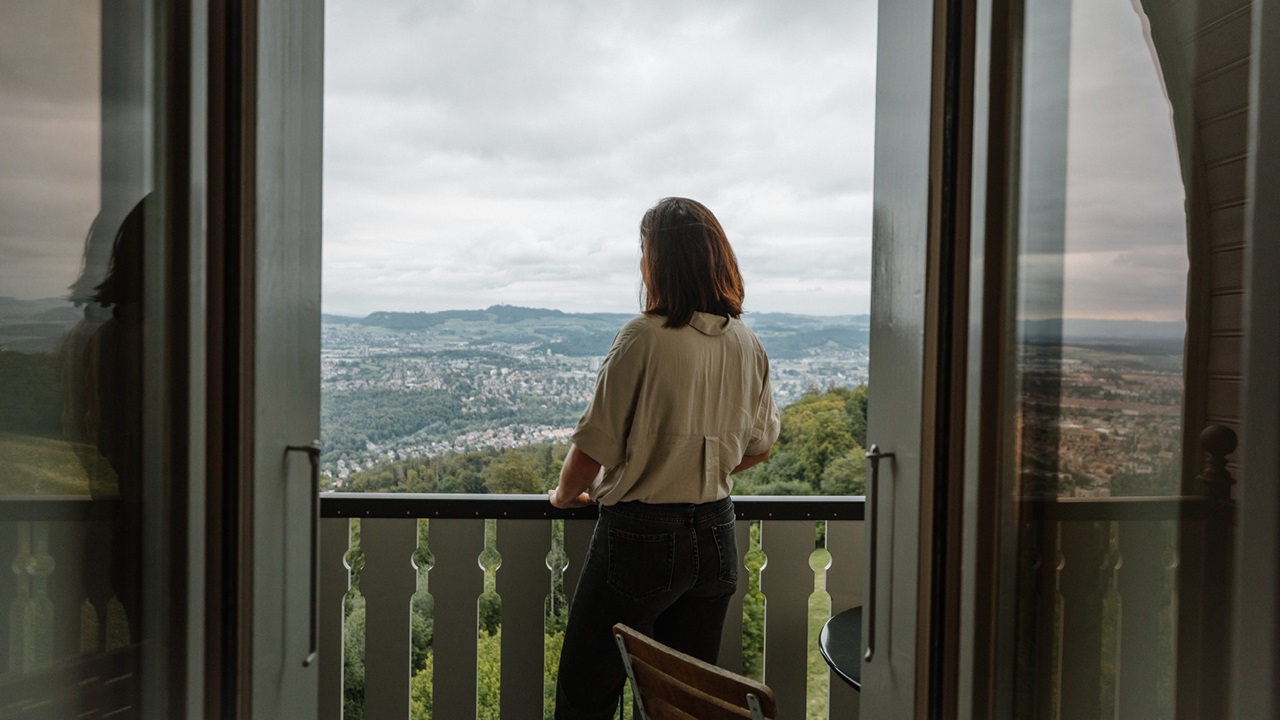 Ein Frau steht auf dem Balkon und geniesst die Aussicht