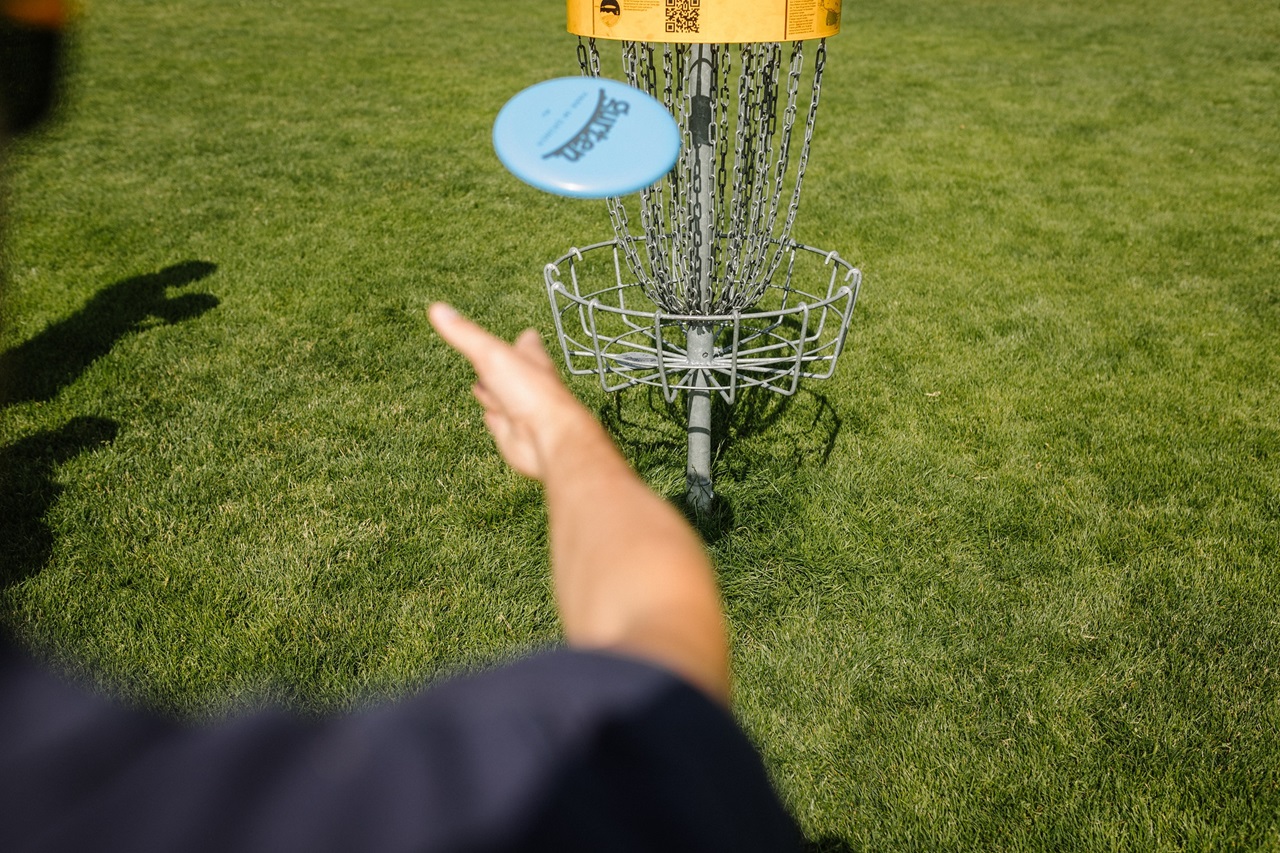 A person throwing a frisbeeA group playing disc golf. A guest throwing a frisbee towards the goal. 