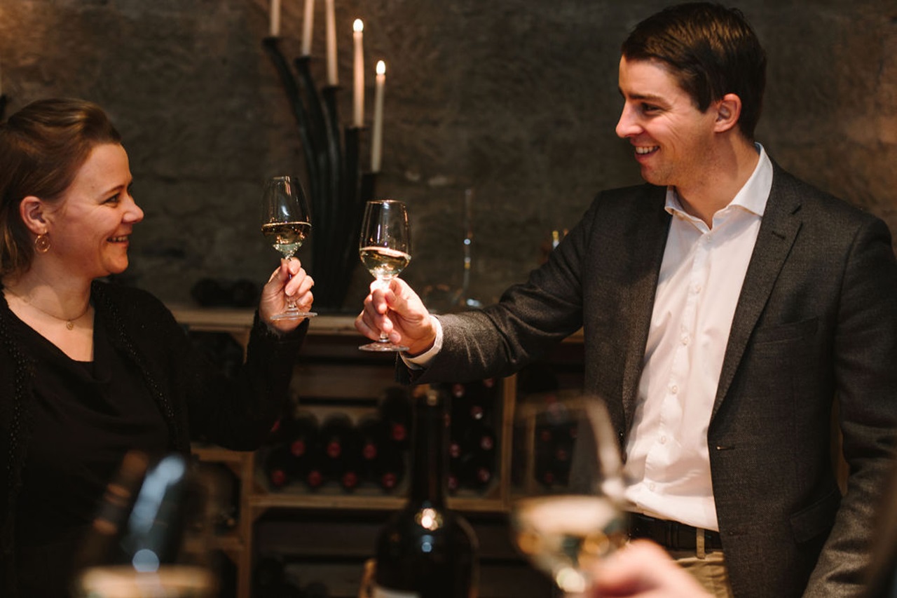 Two people toast in the wine cellar