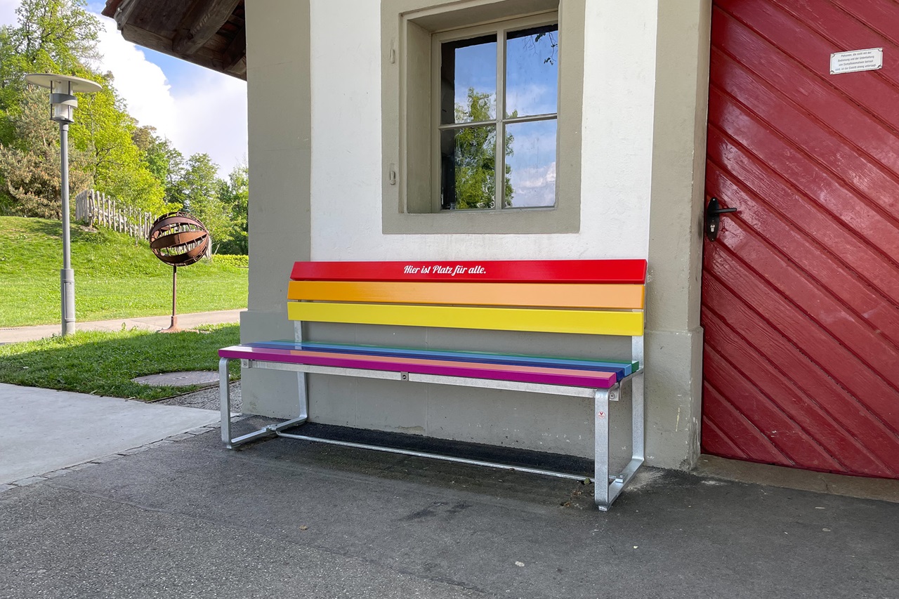 Die Regenbogen-Sitzbank vor einem Haus