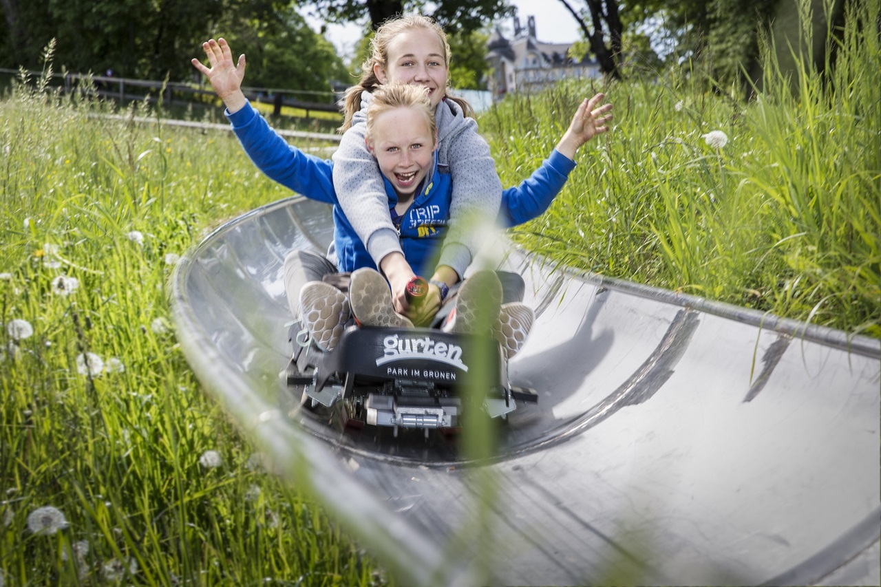 Kinder fahren lachend die Sommer-Rodelbahn hinunter
