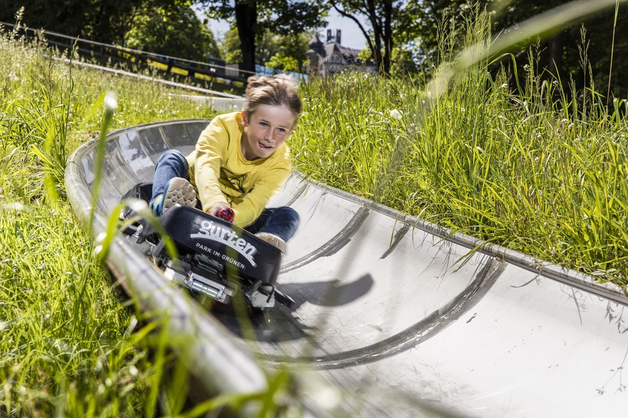 A child riding down the toboggan run in the summer
