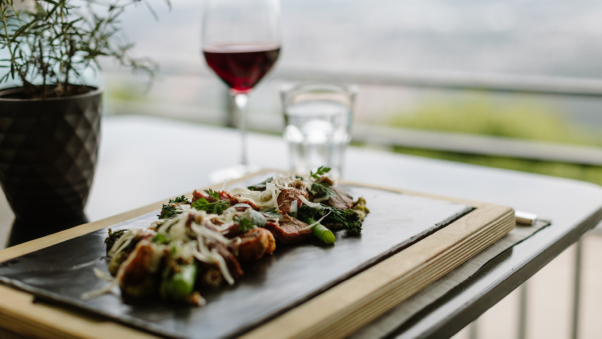 Veal tagliata on a slat serving plate with a glass of red wine