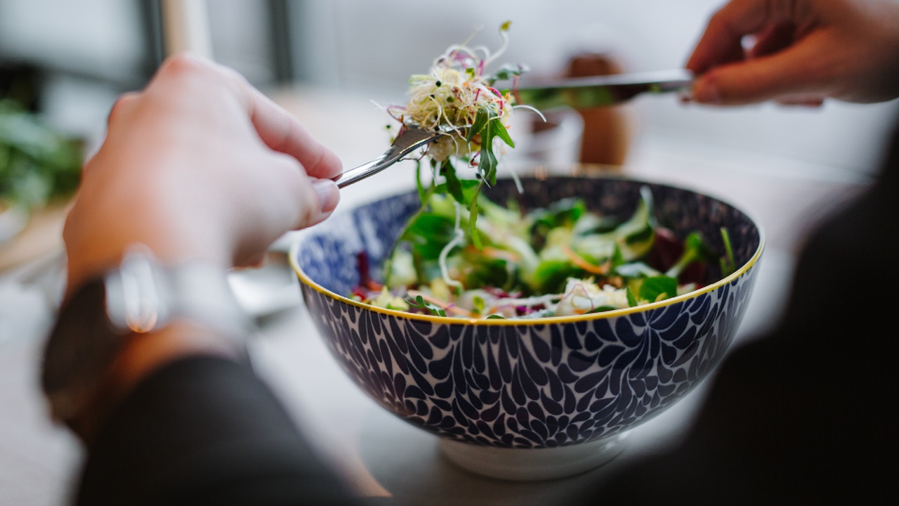 Person isst eine Salatschüssel an einem Fenstertisch im Restaurant Gurtners