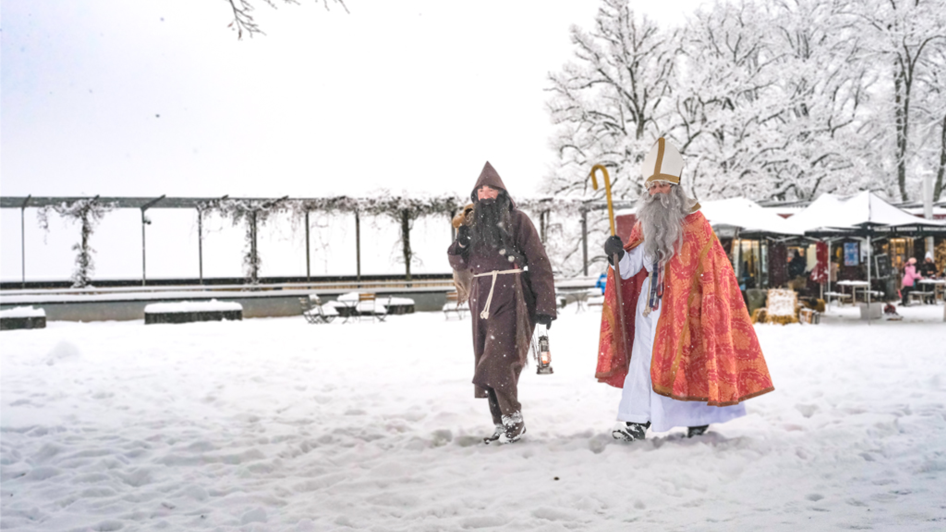Saint Nicholas and his helper walk through the snow