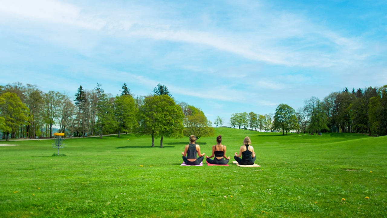 Three women in yoga pose meditating in nature.