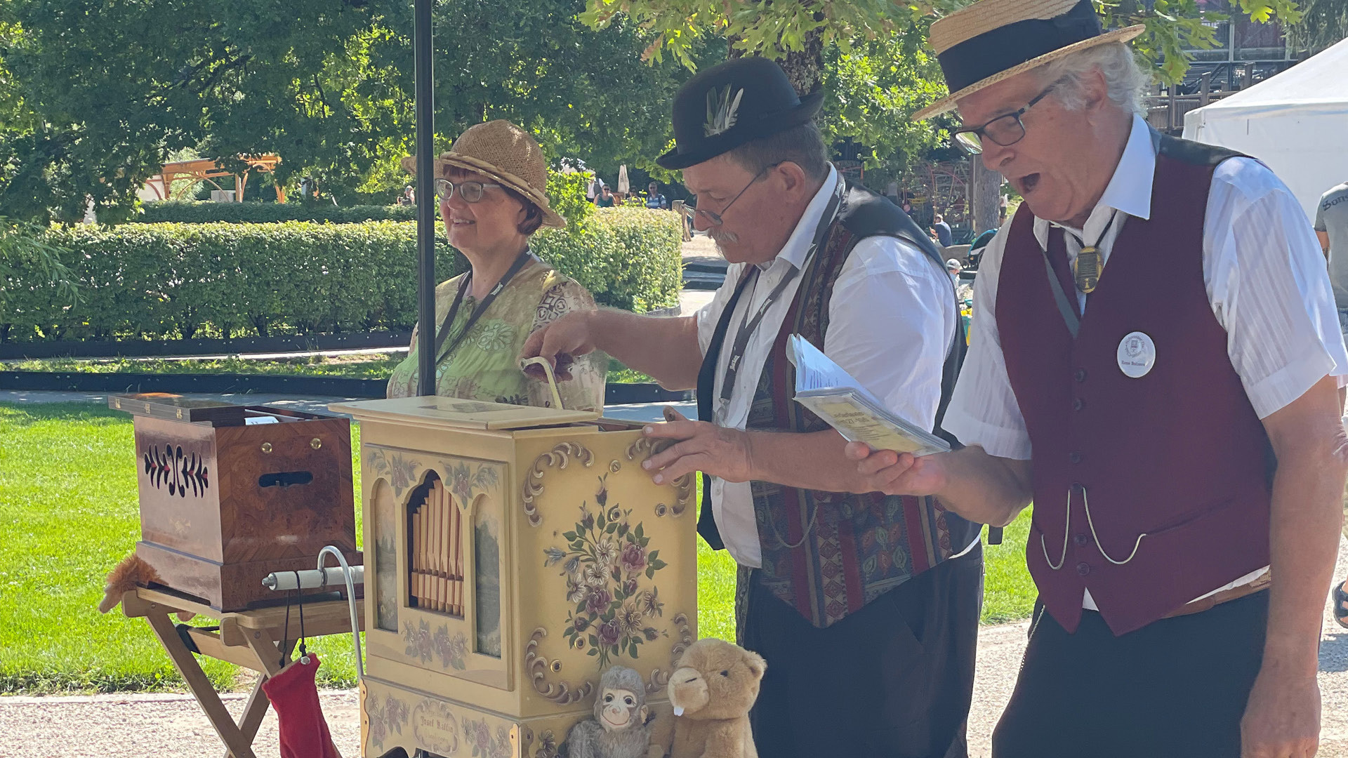 Three people with two barrel organs and one singer.