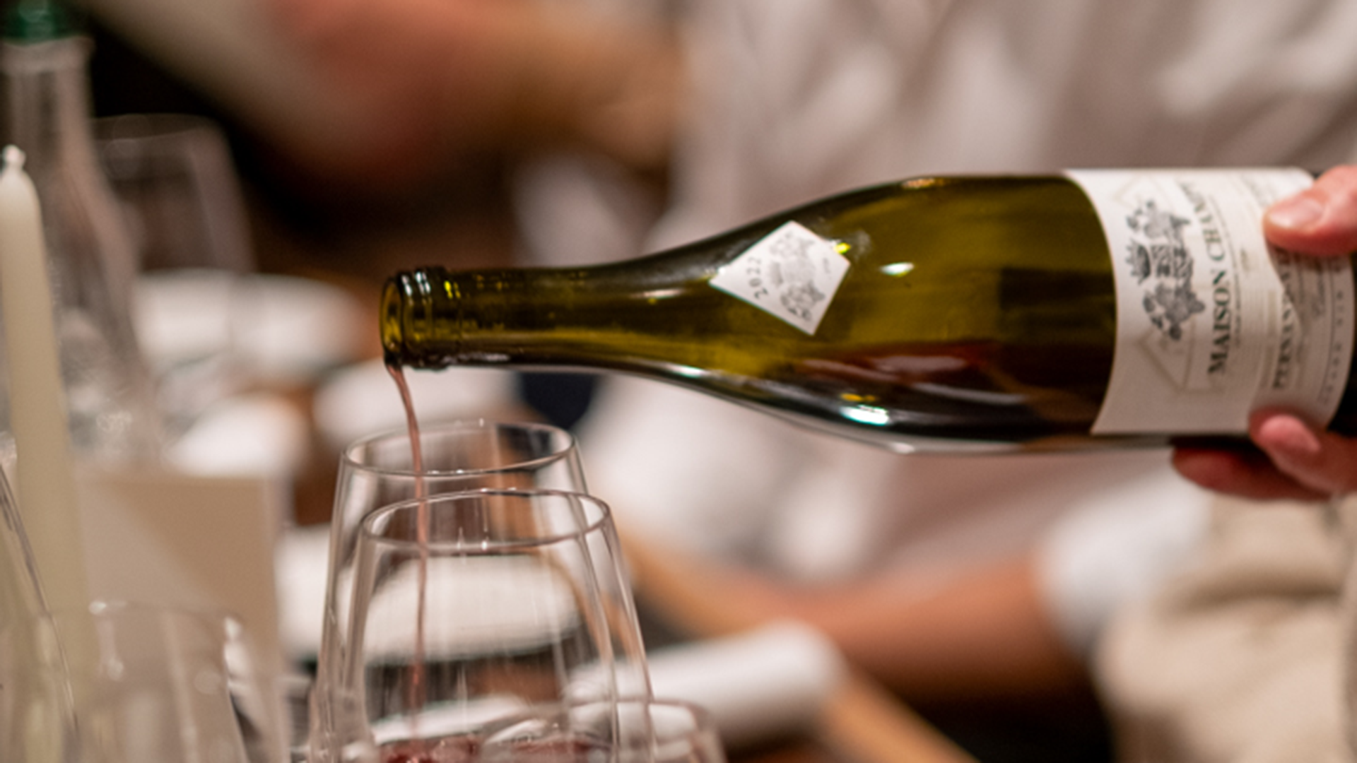 Red wine is poured into wine glasses at the tables in Gurtner's library