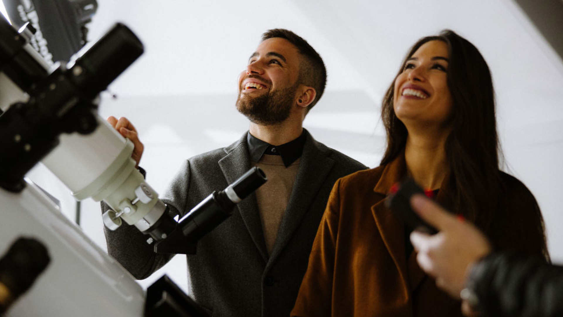 Two people standing in the observatory observing the sky.