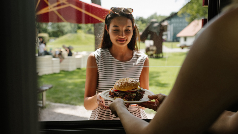Une femme prend un hamburger à la distribution de repas du Bahnhöfli.