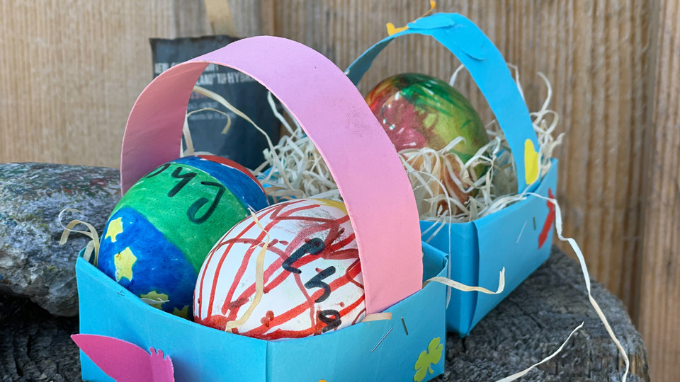 Bemalte Ostereier in kleinen aus Papier gemachten Körbchen.