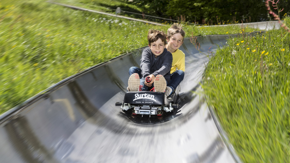 Deux enfants dévalent le circuit de luge d’été sur leur luge