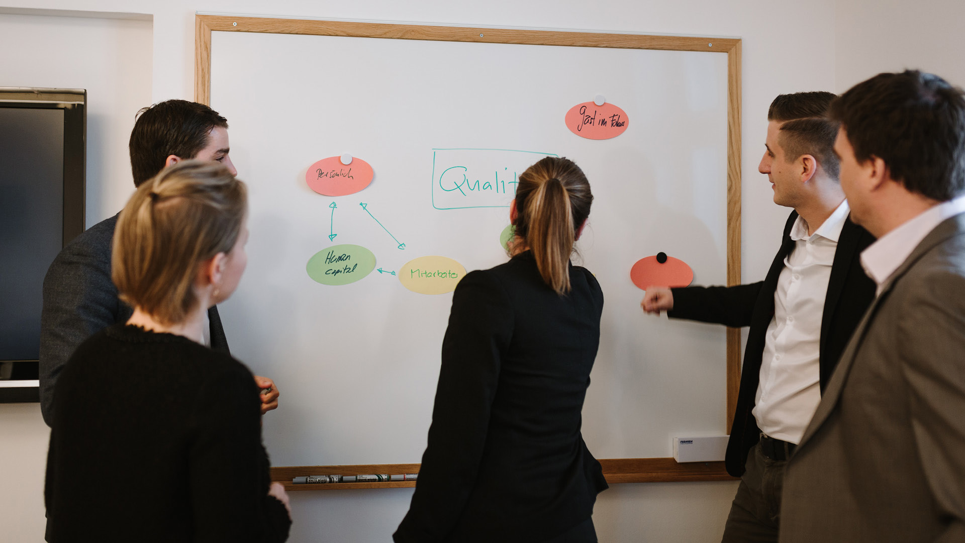 Personen eines Seminar schauen auf ein Whiteboard.