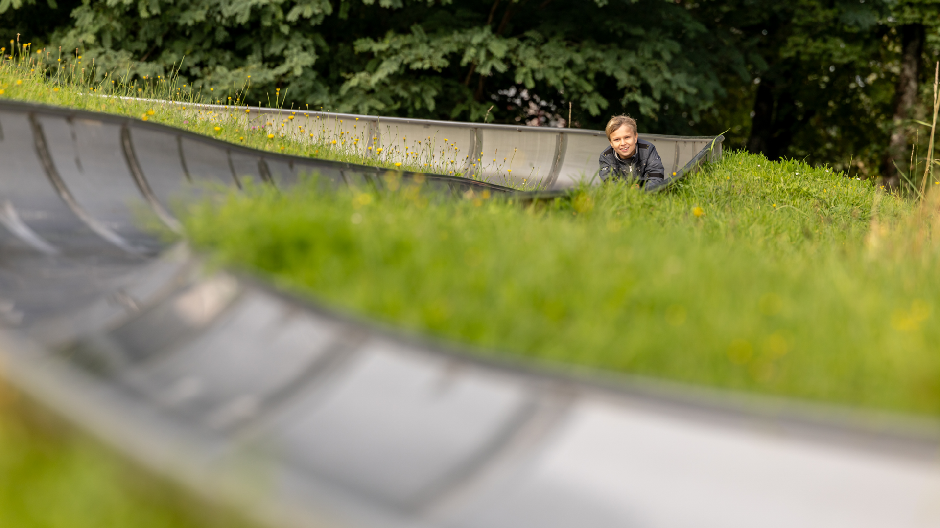 Blurred toboggan run in the foreground, child sledding in the background