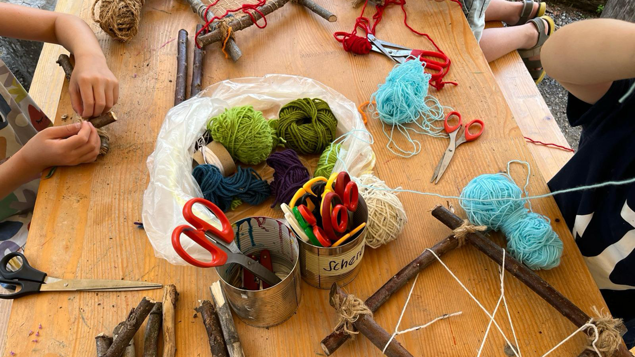 A table at the Gurtengärtli, photographed from above, with craft supplies and children's hands