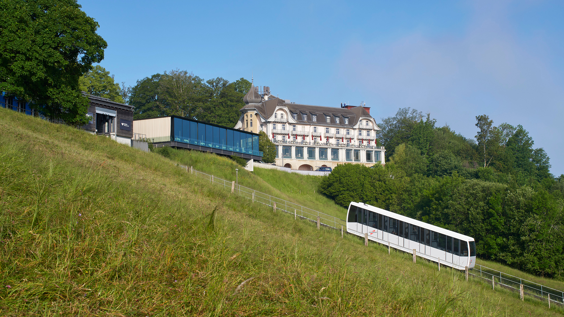 The Gurtenbahn railway during the day in front of the Kulm building and the Pavillon event venue.