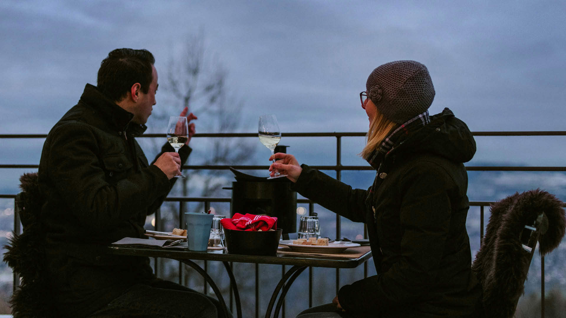 Two people are drinking white wine at a full moon fondue.