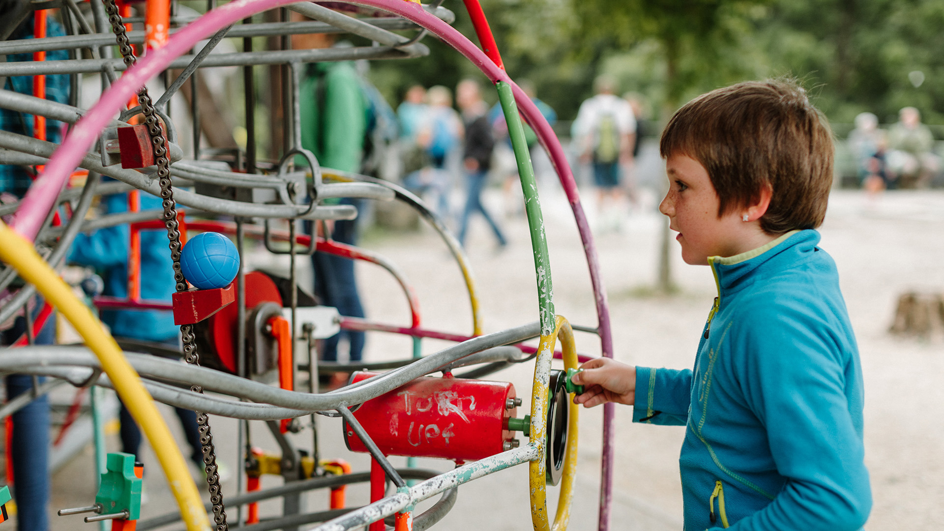 Kind dreht an Kurbel von Kugelbahn in Spielpark