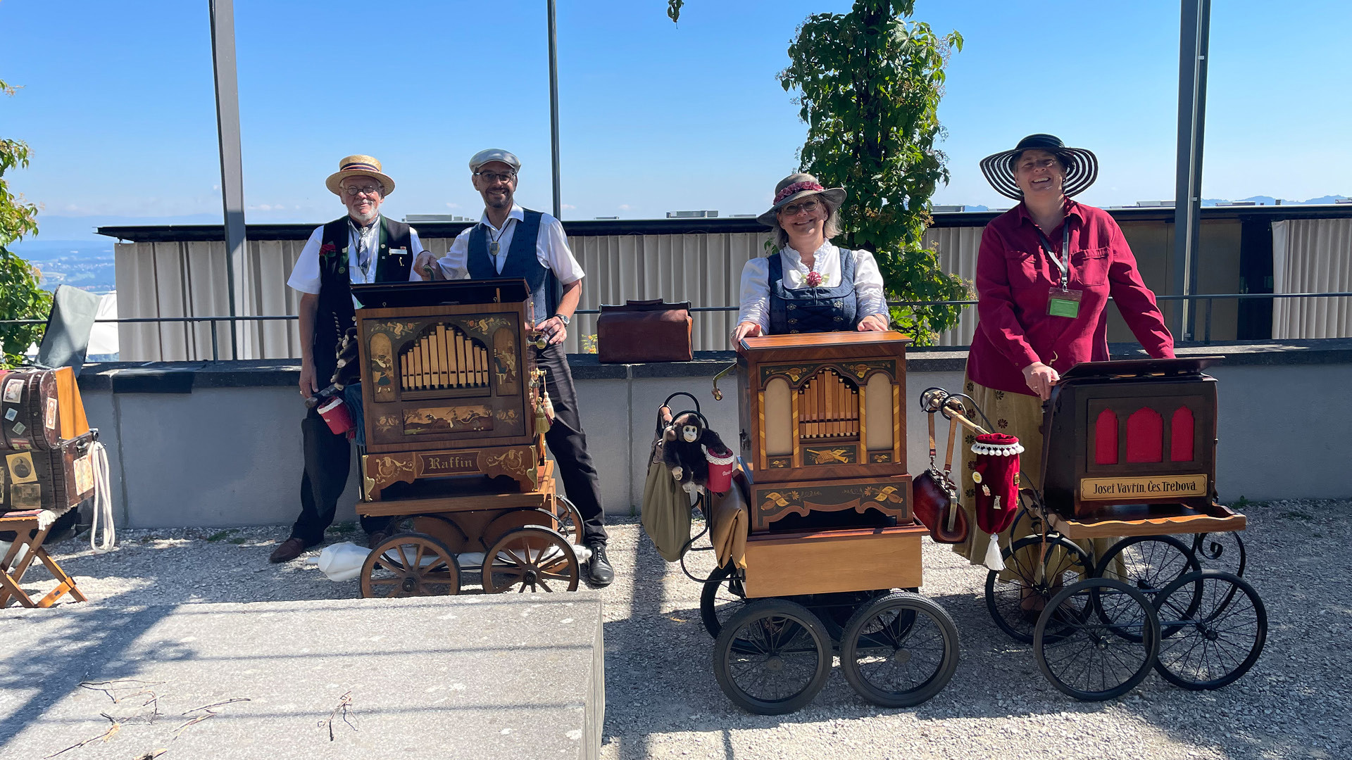Four people with three barrel organs in front of the event location, the Pavillon.
