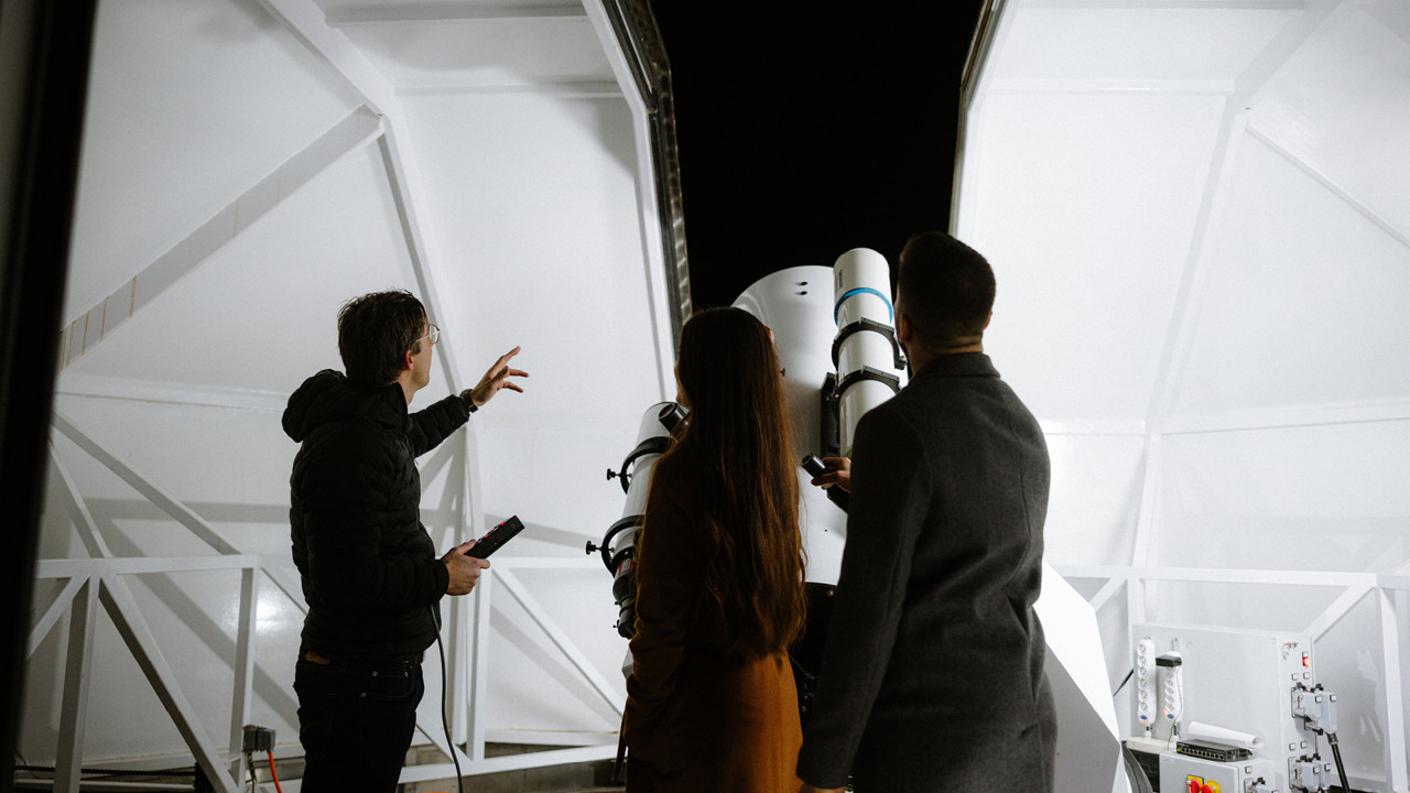 L'intérieur de l'observatoire avec son grand télescope. Un expert d'Astro Events explique le ciel nocturne à deux personnes.