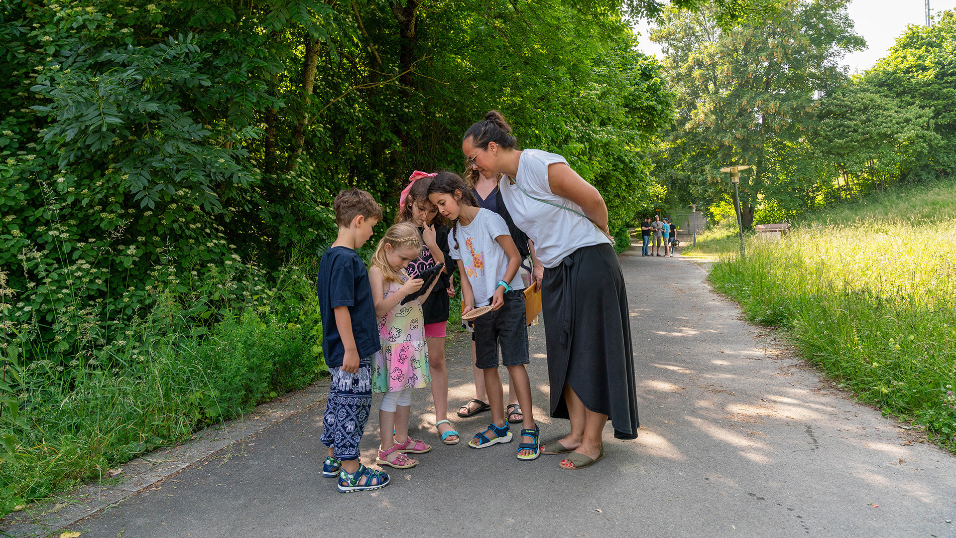 Mehrere Personen schauen alle auf gleiches Tablet bei Outdoor escape Game auf Gurten