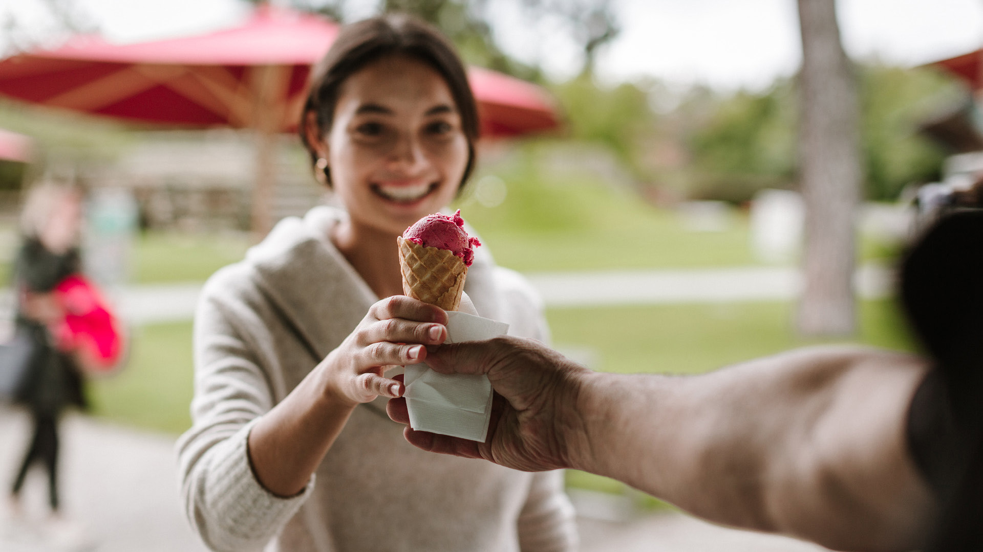 Une personne qui donne une glace à une autre personne. La personne porte un pull beige.