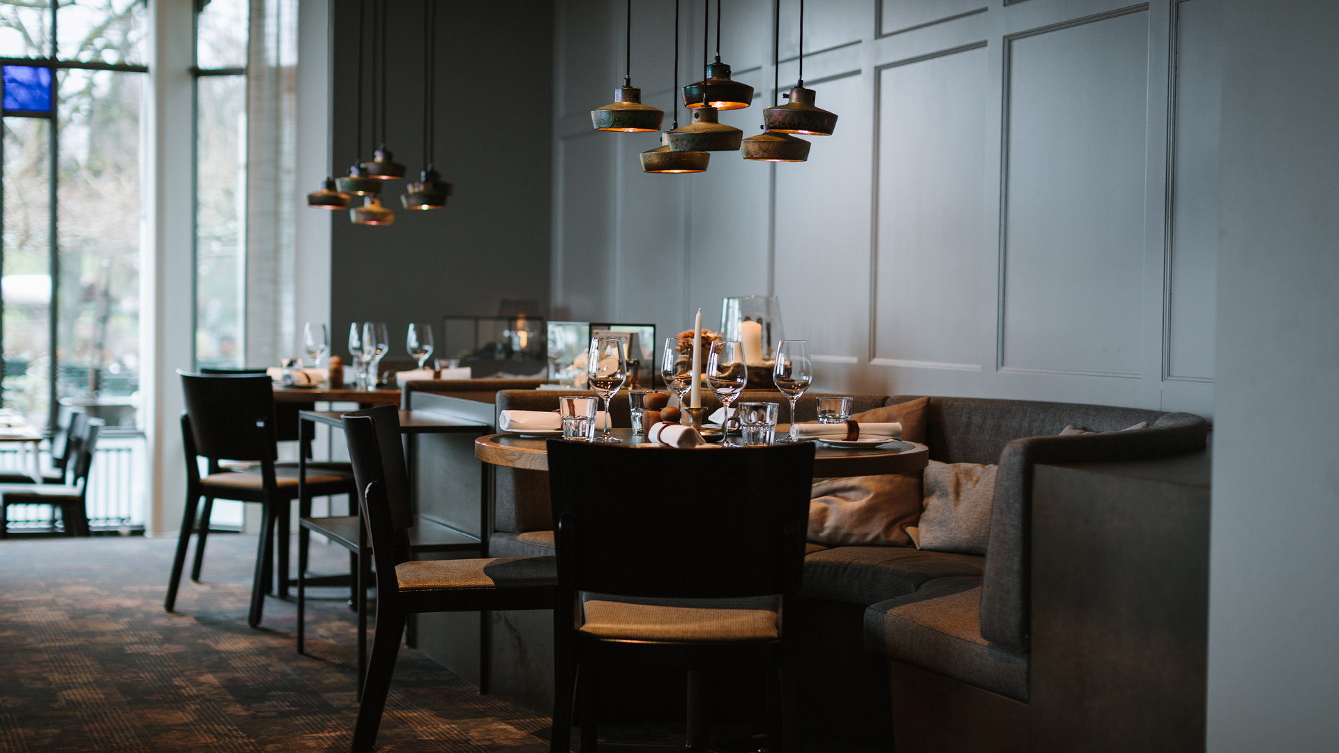 The Stübli at Restaurant Gurtners. Two tables are nicely set and stand in front of a gray wall.