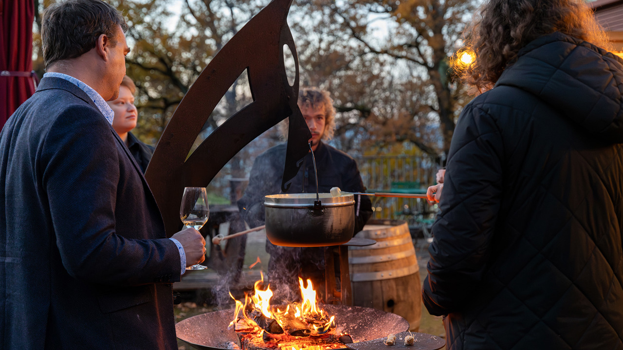 A group gathered around a campfire in the winter village, eating fondue.