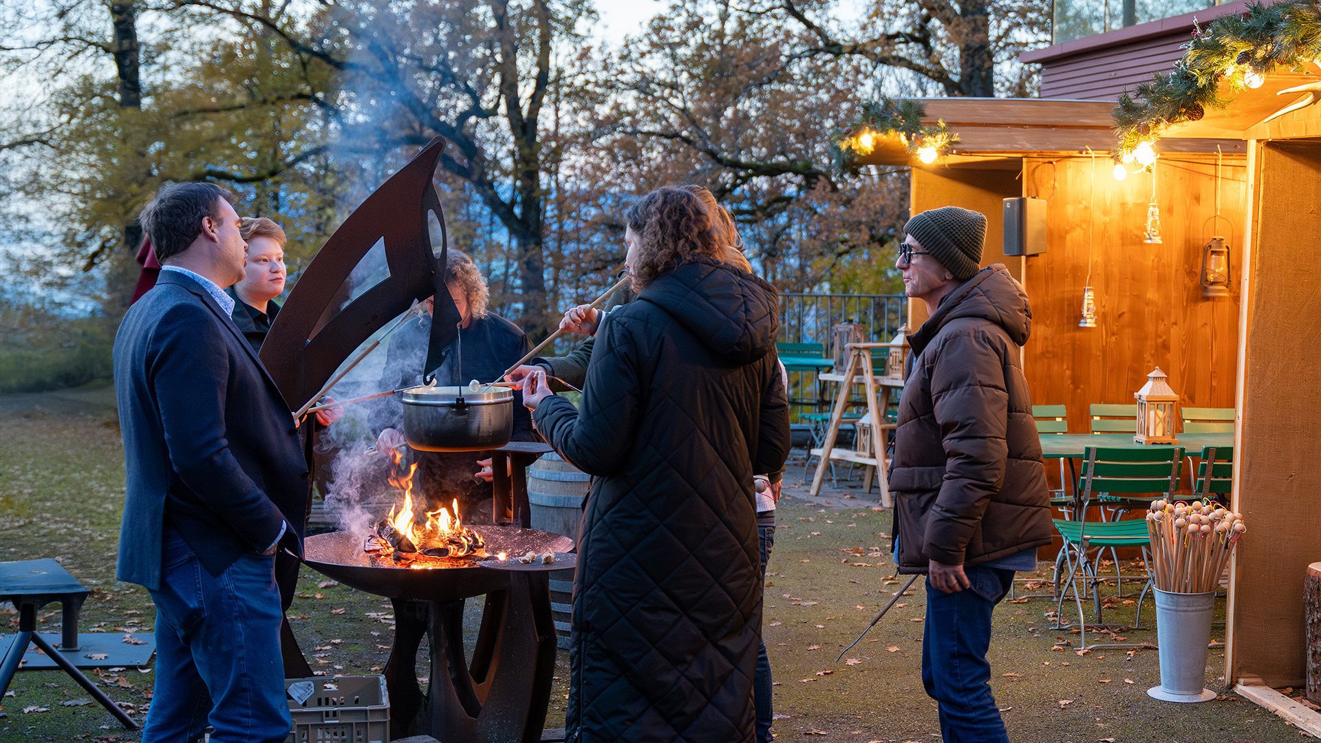 Un groupe autour d'un feu de camp dans le village d'hiver, en train de manger une fondue.